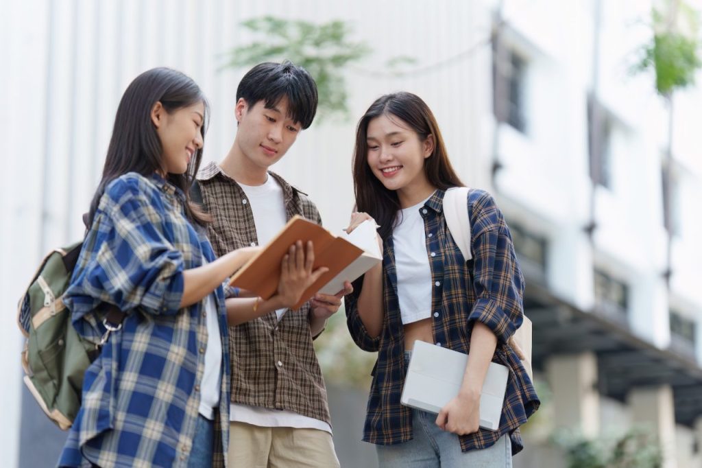 Young asian woman college student with friends at outdoors college student working on the college.jpg